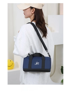 Navy nylon cylinder crossbody bag with JLP logo and adjustable shoulder strap worn by model