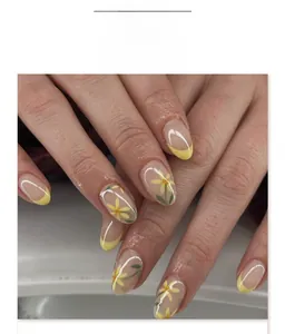 Gros plan d'ongles amande French manucure avec motifs floraux jaunes délicats