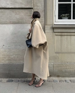 Détail d'un manteau long beige oversize avec col montant et tissu texturé au style urbain