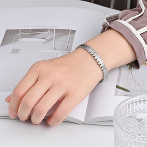 Close-up of silver stainless steel leaf pattern bracelet on a model's wrist with modern aesthetic