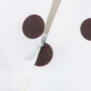 Détail d'une robe blanche à pois avec une fermeture à glissière invisible de qualité