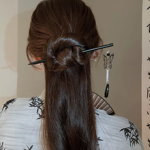 Detail of a vintage Chinese butterfly hair pin with tassels worn on a bun hairstyle