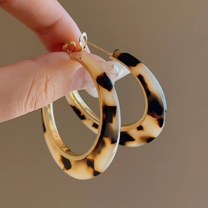 Close-up of leopard print acrylic hoop earrings with gold-toned inner metal frame