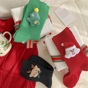 Close-up of festive knit Christmas socks with plush Santa and reindeer doll patches