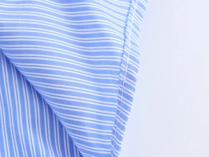 Close-up of blue striped cotton linen shirt fabric texture and fine stitching detail