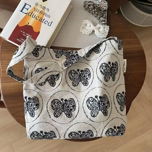 Detail of canvas shoulder bag with butterfly pattern and simple wish label