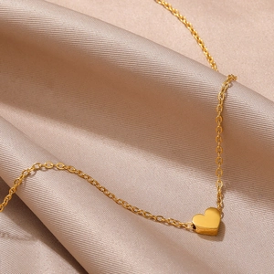 Elegant gold-tone heart pendant necklace on champagne satin fabric, minimalist jewelry style