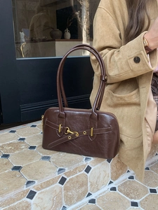 Close-up of brown faux leather bowling bag with gold metal buckle and dual straps