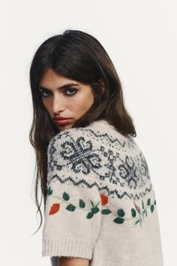 Detail of Nordic geometric patterns and colorful embroidery on a knit short sleeve sweater