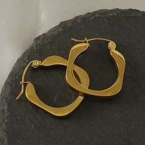 Detailed close-up of 18k gold-plated irregular square hoop earrings on a textured stone