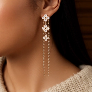 Detail of 18K gold plated flower earrings with long tassels on an elegant model