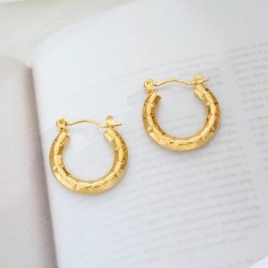 Close-up of 18K gold plated hoop earrings with textured diamond-cut geometric facets