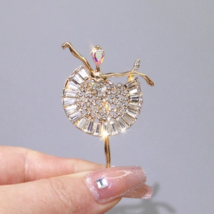 Detailed close-up of a golden ballerina brooch with rhinestones and a colorful gem