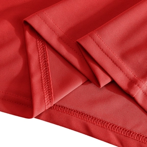 Detail of red pique polo shirt fabric showing breathable mesh texture and double stitching