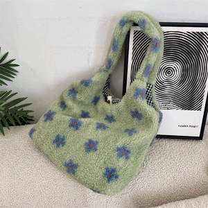 Close-up of green plush tote bag with blue floral patterns and checked lining detail
