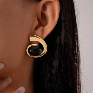 Gros plan sur une boucle d'oreille rétro en gemme noire avec motif spirale doré chic