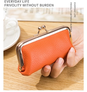 Detailed view of orange lychee grain leather coin purse with golden metal clasp closure