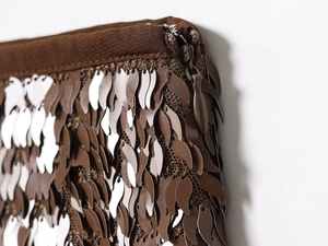 Détail macro de paillettes bronzes et zip invisible sur une jupe courte marron