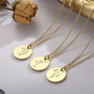 Détails macro de pendentifs dorés gravés de fleurs avec fines chaînes en acier