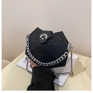 Detail view of black geometric handbag with embossed texture and silver C-shaped metal buckle