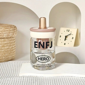 Detail of ENFJ glass straw cup with tea strainer and pink lid on a minimalist shelf