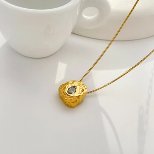 Detailed macro of golden irregular lava pendant with cubic zirconia on box chain