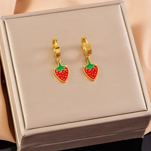 Golden strawberry pendant earrings with red enamel on luxury jewelry box display