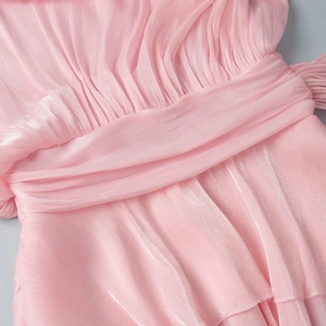Detailed view of pink pleated chiffon fabric with shimmery texture and layered ruffles
