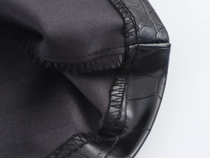 Detailed macro view of black PU leather with embossed crocodile texture and fine stitching