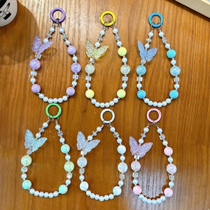 Luminous butterfly beaded phone straps in six colors displayed on a wooden surface.