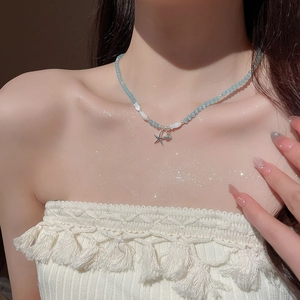 Gros plan d'un collier en opale avec pendentifs étoile de mer et coquillage