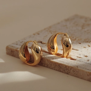 Elegant gold plated waterdrop hoop earrings displayed on a minimalist beige marble block
