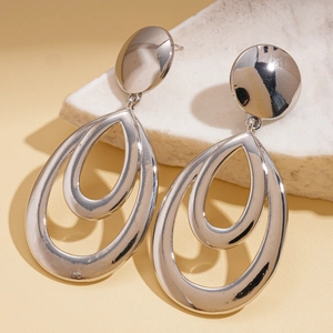 Macro shot of silver teardrop earrings on marble, featuring hollow layered geometric design