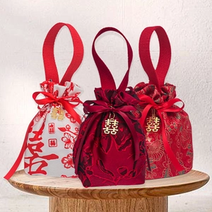 Detailed view of three red Chinese wedding candy bags with silk ribbons and gold pendants