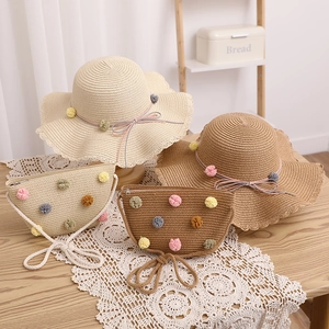 Close-up of summer straw hat and matching bag set with colorful decorative pom-poms