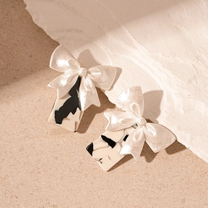 Close-up of vintage resin bow earrings with black and white marble pattern