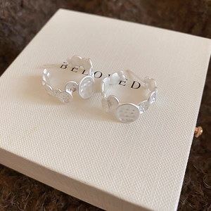 Detail view of silver C-shaped earrings with irregular hammered metal discs on jewelry box