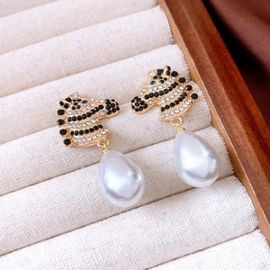 Detail of zebra head earring with sparkling crystals and large drop pearl on tray