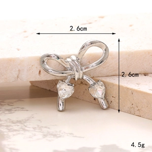 Silver bow shoe charm with heart gemstones showing dimensions 2.6cm x 2.6cm and 4.5g weight
