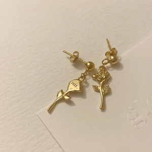 Detailed view of S925 sterling silver golden rose stud earrings on textured white paper
