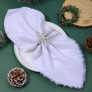 Detailed view of silver snowflake napkin ring with crystals on a white linen napkin