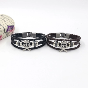 Detail of multilayer leather bracelets with punk skull charms and metallic beads