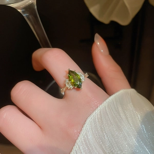 Detail view of a 14K gold plated marquise emerald ring with sparkling diamonds on a finger