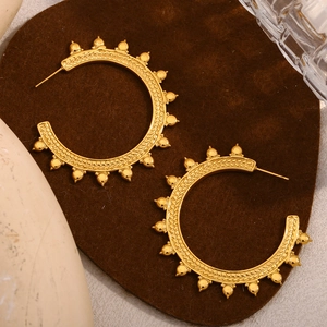 Close-up of gold boho hoop earrings with studded beads and textured weaving on suede