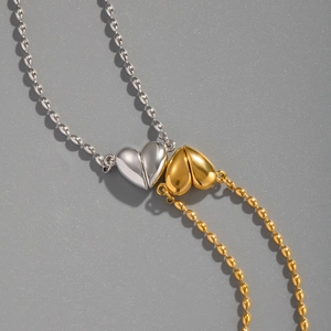 Détail de pendentifs en forme de cœur imbriqués sur des colliers à billes or et argent