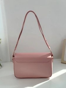 Detail of pink faux leather shoulder bag featuring minimalist flap and gold metal buckle