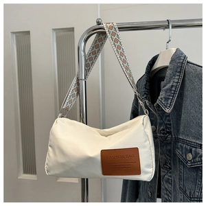 Detail of white nylon shoulder bag featuring brown fashion label and wide patterned strap