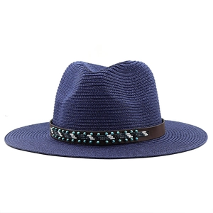 Detailed close-up of blue straw fedora hat featuring ethnic beads on a leather band