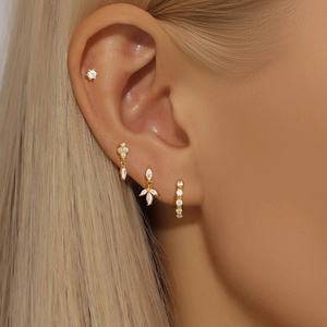 Close-up of gold earrings set with marquise stones and clear zircons on a model
