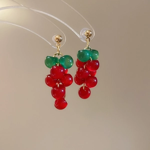 Macro view of long resin grape cluster drop earrings featuring green and red beads